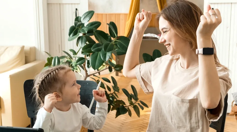 Mutter und Kind üben gemeinsam und freuen sich, Sprachförderung im Familienalltag zuhause