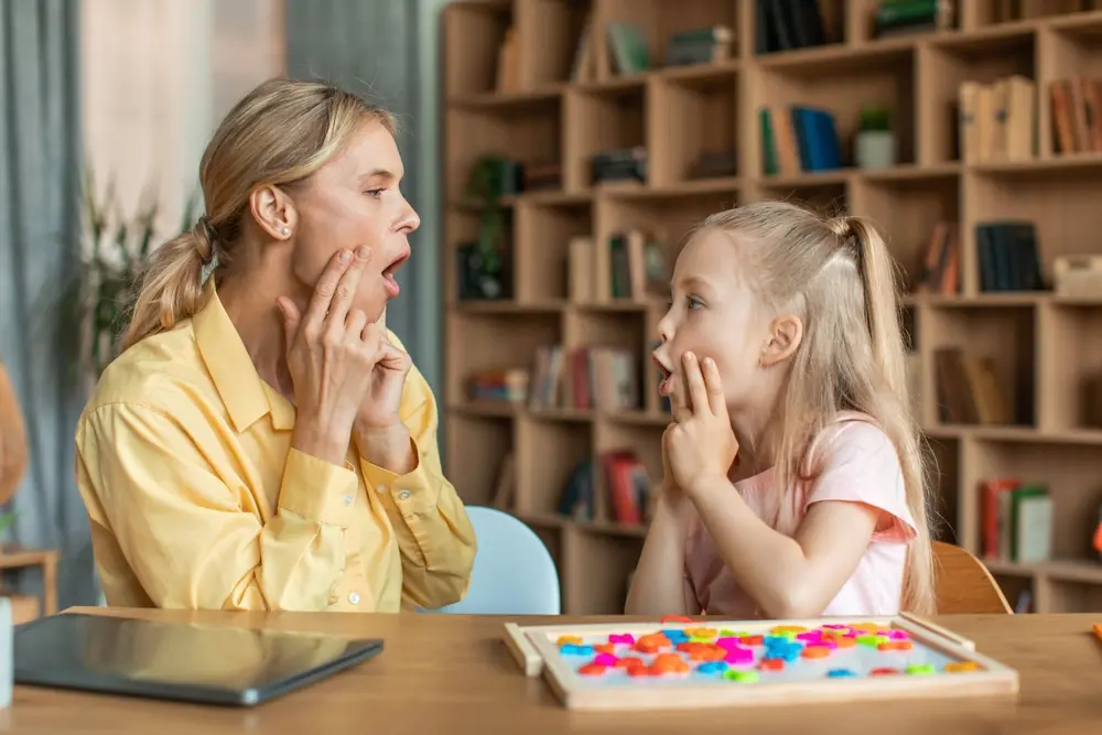 Sprachtherapeutin übt mit einem Kind spielerisch die Aussprache